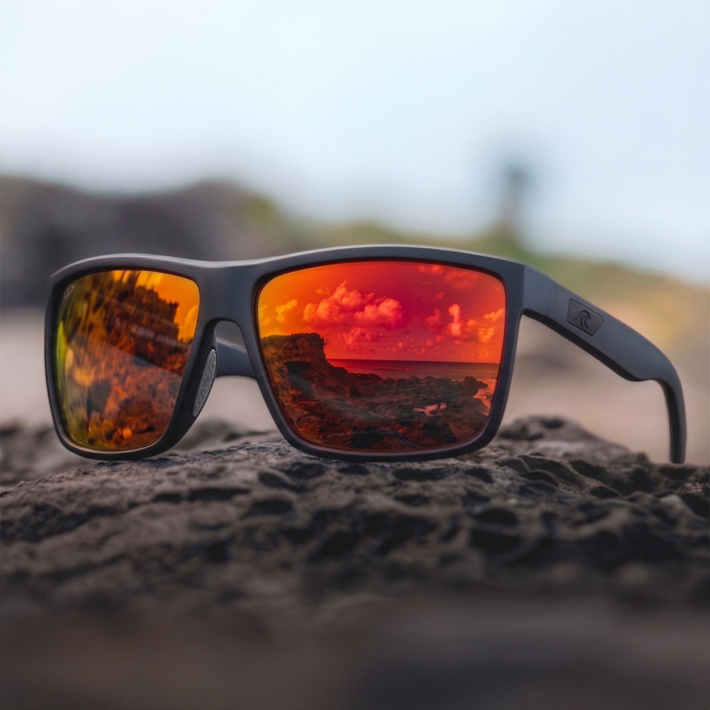 Sunglasses with reflective red lenses on a rocky surface, with a blurred natural background
